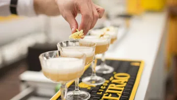 Hand garnishing cocktails with flowers.