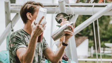 Person holding drink mixers outdoors.