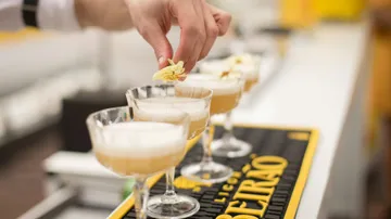 Hand placing flower on cocktail glasses.