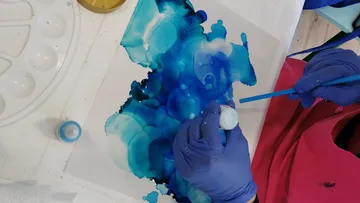 Person painting abstract blue artwork.