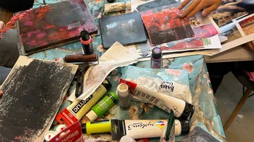 A table with art supplies and paintings.
