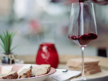 Rotwein wird in ein Glas gegossen, umgeben von Snacks.