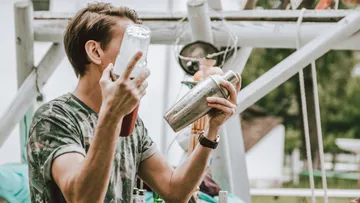 Person, die draußen einen Cocktailshaker in der Hand hält