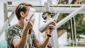 Person shaking cocktail shaker outdoors.