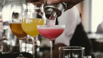 Cocktailshaker, der rosa Drink in ein Glas gießt.