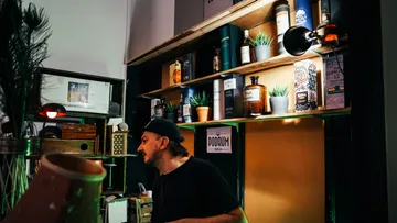 Mann in einer Bar mit Getränkeregalen.