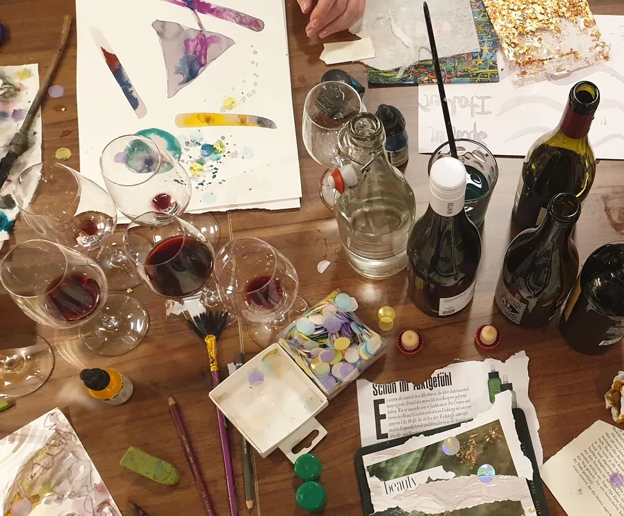 Art supplies and wine glasses on table.