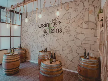 Holzfässer stehen in einem stilvollen Weinsalon mit Beleuchtung.