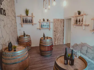 There are wooden barrels in the room, decorated with bottles and plants.