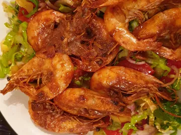Boiled shrimps lie on fresh vegetable salad.