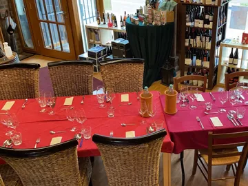 Large table with cutlery, glasses and red tablecloths.