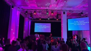 Crowd watching karaoke lyrics under purple lights.