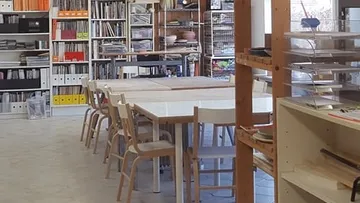 Bibliothek mit langem Tisch und Regalen.