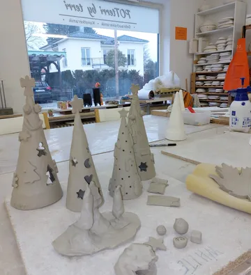 Weihnachtsbaumskulpturen aus Ton auf dem Werkstatttisch.