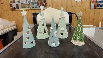 Bunte Keramik-Weihnachtsbäume sind ausgestellt.