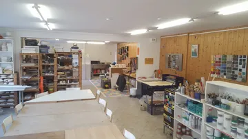Bright pottery studio with tables and shelves.