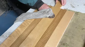 Person, die ein Holzschneidebrett poliert.