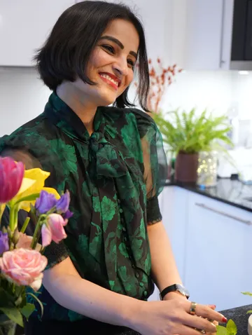 Lächelnde Frau mit Blumen in der Küche