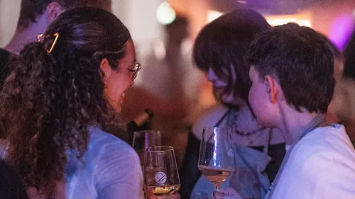 People talking while holding wine glasses.