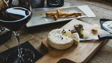 Käse und Wein mit Grissini auf dem Tisch.