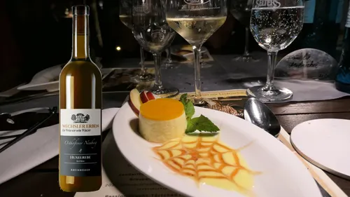 Wine bottle beside dessert on table with drinks.