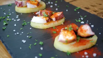 Tintenfisch- und Kartoffel-Tapas auf Schieferplatte.