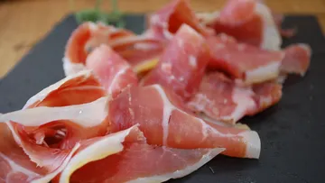 Thinly sliced prosciutto on slate board.