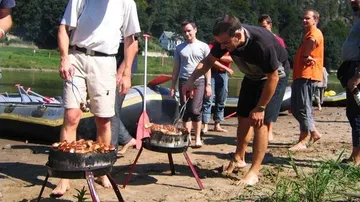 Leute, die Würstchen am Fluss grillen.