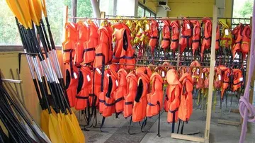 Orangefarbene Schwimmwesten und Paddel sind drinnen organisiert.