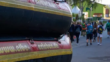 Gestapelte Schlauchboote auf dem Bürgersteig, Leute gehen vorbei.