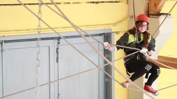 Person, die bei einer Indoor-Aktivität an Seilen sitzt