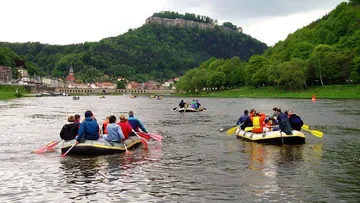 People rafting on a river near mountains.