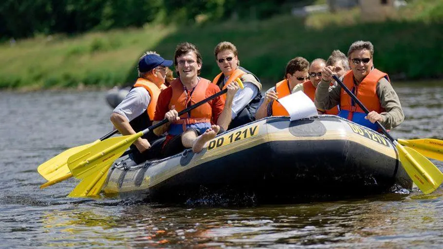 Group rafting on a river, wearing life jackets.
