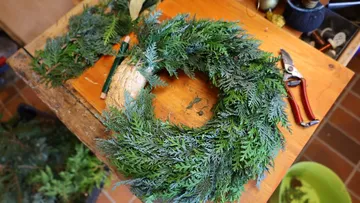 Fresh evergreen wreath on wooden table