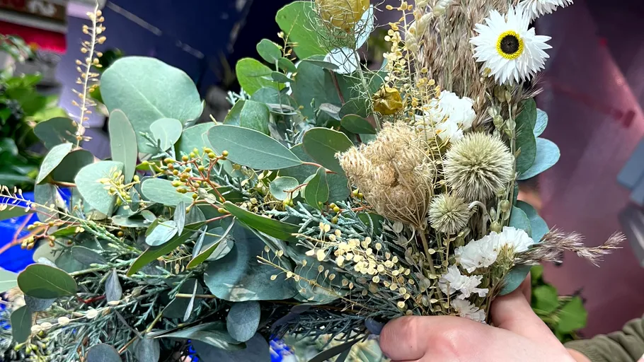 Hand holding mixed dried flower bouquet.