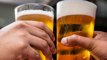 Zwei Hände klirren Biergläser aneinander.