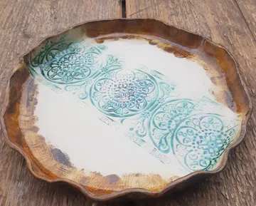 Decorative ceramic plate with green patterns on wood.