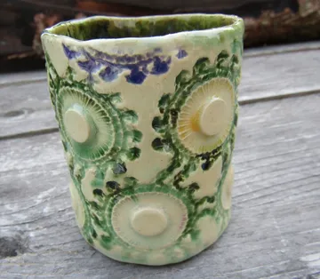 Textured ceramic cup with green floral design.