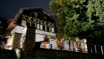 Illuminated house exterior at night with trees.