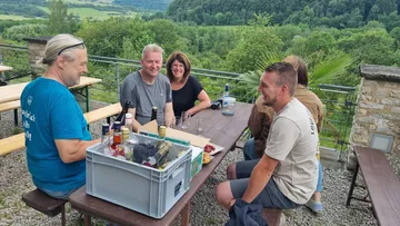 Gruppe sitzt draußen am Picknicktisch.