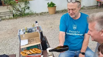 Mann schenkt Getränke in der Nähe des Picknicktisches mit Brezeln ein.