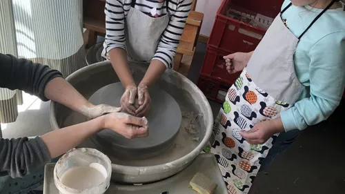 Two people making pottery on a wheel.