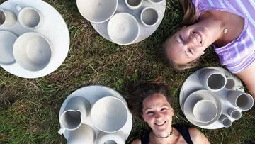 Zwei Frauen mit Keramikkeramik auf Gras.