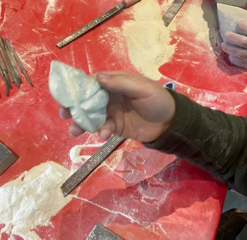 Hand holding carved stone on red table.