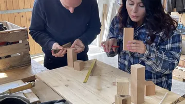 Two people crafting wooden blocks indoors.