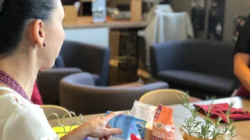 Person holds product bags in cozy room.