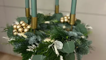 Grün-goldener Blumenkranz mit Kerzen.