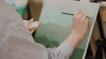 Person painting green shades on canvas.