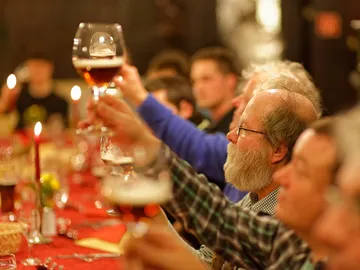 Glasses are raised; festive atmosphere at a table.