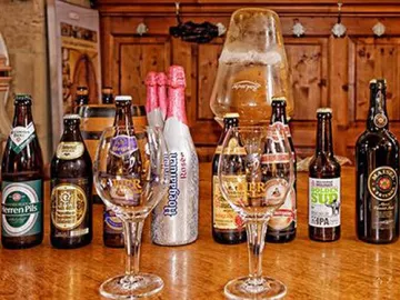 Beer bottles and glasses are on a wooden table.